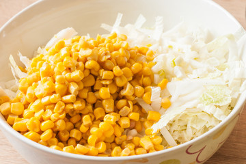 Adding canned corn to white cabbage salad