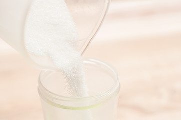 Pouring white sugar into a smaller container for ease of use