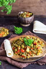 Green lentil stew (curry) with apple, bell pepper and onion. Selective focus. Dark stone background, rustic style.