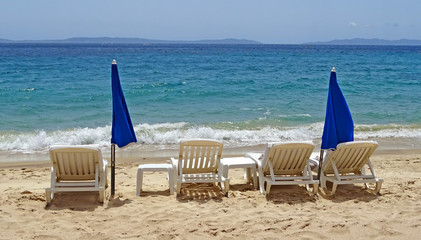 beach with white sun lounges and blue parasols