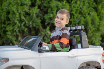 Little boy smiling holding the wheel of the car.child boy is playing in the front seat of the  car and smiles sincerely