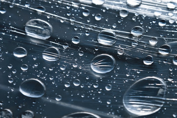 Close-up of raindrops of different sizes on the surface covered with cling film. Moisture weather...