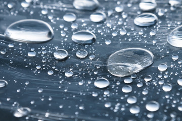 Close-up of raindrops of different sizes on the surface covered with cling film. Moisture weather and humidity concept