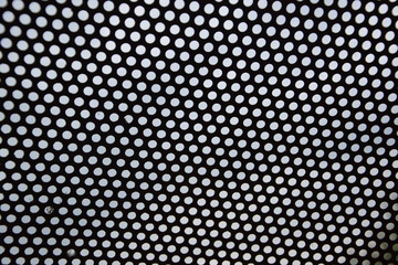The photo shows the texture of a metal plate with holes facing the sky.