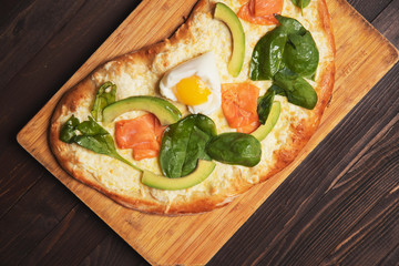 Pie with avocado and salmon on wooden background, top view