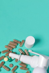 Gelatin pills and tablets of different colors. Sprays of oral and nasal sprays. Medicines scattered on the background of coral color.