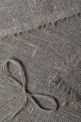 Fototapeta premium Coarse linen fabric. On it lies a bow of linen thread.