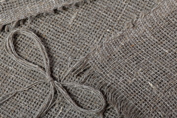 Fototapeta premium Coarse linen fabric. On it lies a bow of linen thread.