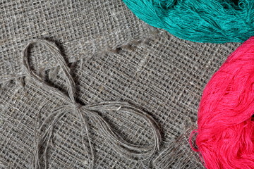 Coarse linen fabric. On it are hanks of colored threads. On it lies a bow of linen thread.