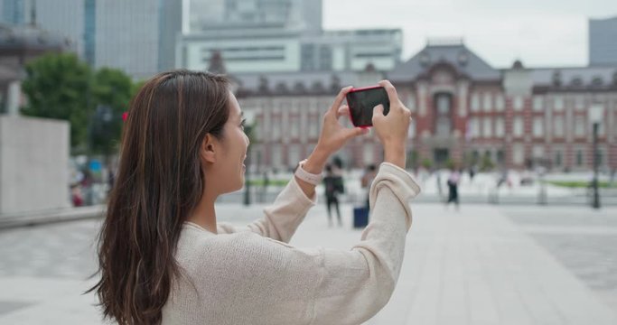 Woman take photo on cellphone in Tokyo station