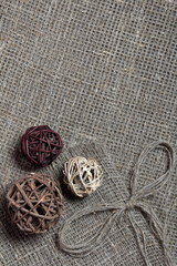 Coarse linen fabric. On it are rattan balls and a bow of linen threads.