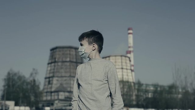 A boy Wearing Pollution Mask Against Smoke Emitting From Factory Chimneys. Air pollution concept.