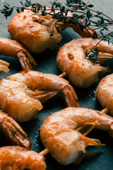 Three shrimp skewers with thyme sprig on the top