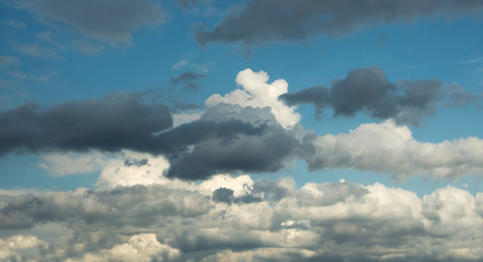 White curly clouds mixed with dark clouds against the blue sky