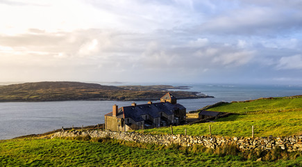 Fototapeta premium Green fields and houses on the coast, coastline and islands in a distance, Wiled Atlantic Way