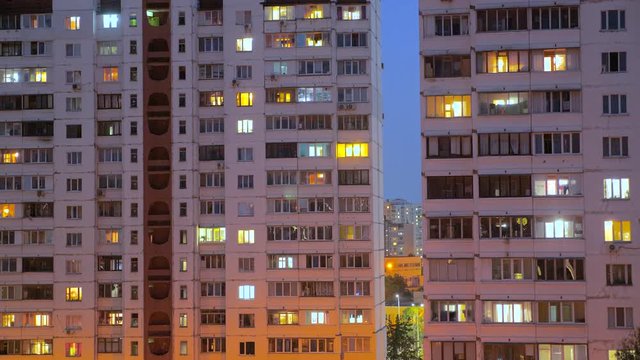 Timelapse of apartment windows at dusk to night. Nighttime time lapse of illuminated building windows at night with people living in flats with balcony. View from below. Business center outdoor