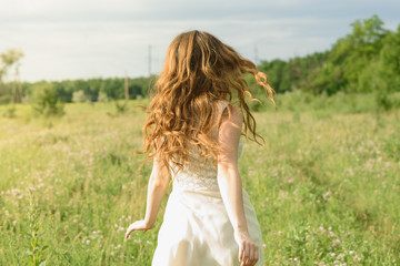Fototapeta na wymiar Beautiful and happy young girl running on the green field in a white dress