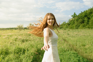 Fototapeta na wymiar Beautiful and happy young girl running on the green field in a white dress