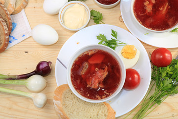 Traditional Russian borsch with egg and bread on a wooden table. Delicious traditional natural food, top view, selective focus.