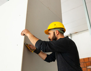 Worker builds a plasterboard wall.