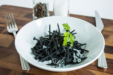Black metal nails on a white plate