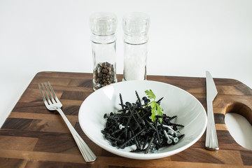 Black metal nails on a white plate