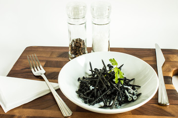 Black metal nails on a white plate