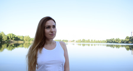 Portrait of a young girl in a white t-shirt near the lake. Nature and man.