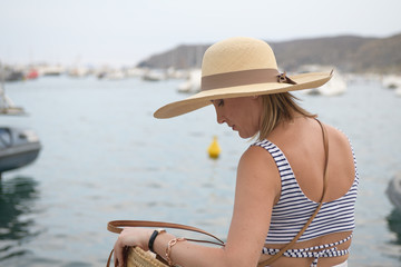 Back view of a woman with a hat looking for something in her bag over seaside promenade