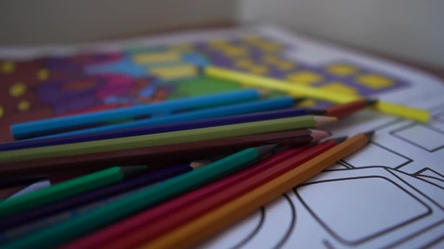 Colored pencils are on the children's coloring with cars