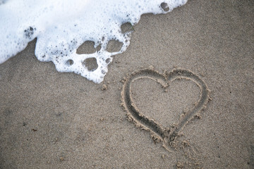 heart in sand with wave close up