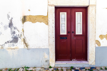 Old European aged house front with deep red wooden doors.