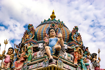 Naklejka premium Colourful sculptures of expressive hindu deities above a temple.
