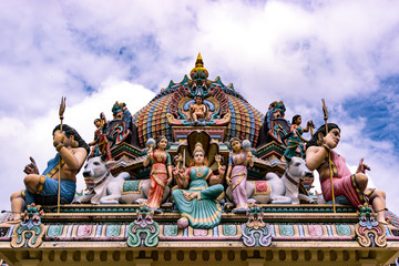 Colourful sculptures of expressive hindu deities above a temple.