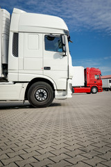 Ein rotes und ein weißes Führerhaus eines LKW`s stehen nebeneinander 