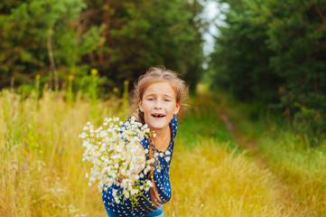 Little cute girl gathers a bouquet of wild flowers on a summer day in the field