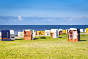 Verschlossene Strandkörbe stehend auf einer Wiese und am Strand 