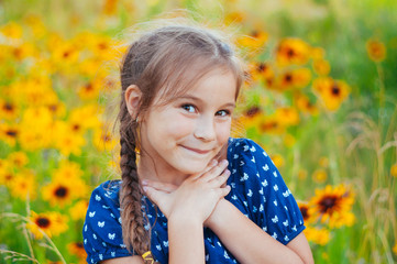 Portrait of a little adorable little girl smiling, in field with yellow flowers