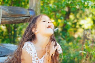 Emotional portrait of a little girl with long hair, summer day