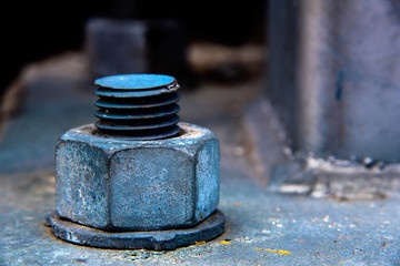 Close-up of a weathered nut bolt and washer firmly fixed into a concrete base