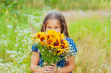 Little adorable girl gathered a bouquet of wild flowers