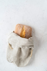 Fototapeta na wymiar Homemade bread stored in a reusable linen bag with drawstring. Eco friendly Zero waste concept.