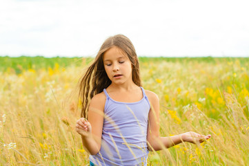 Portrait of a little adorable little girl smiling, in field with yellow flowers