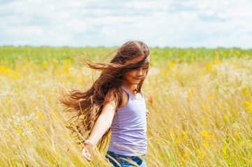 little adorable girl with long hair in the field enjoying the summer