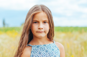 portrait of a little adorable girl with long hair in the field