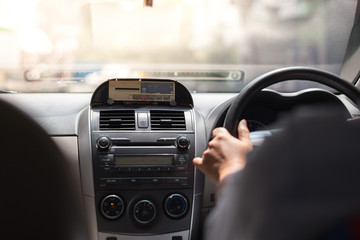 Men's hand holding the steering wheel and meter in taxi with sunlight