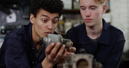 4K Young engineers in workshop assembling auto parts and discussing