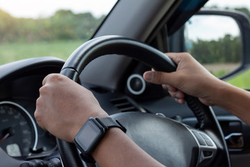 Hand of man driving inside car and blur nature background.