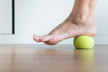 Women massage with tennis ball to her foot,Feet soles massage for plantar fasciitis