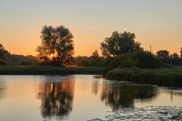 Fototapeta na wymiar Beautiful sunrise on the lake, the path of the Sun burns with gold